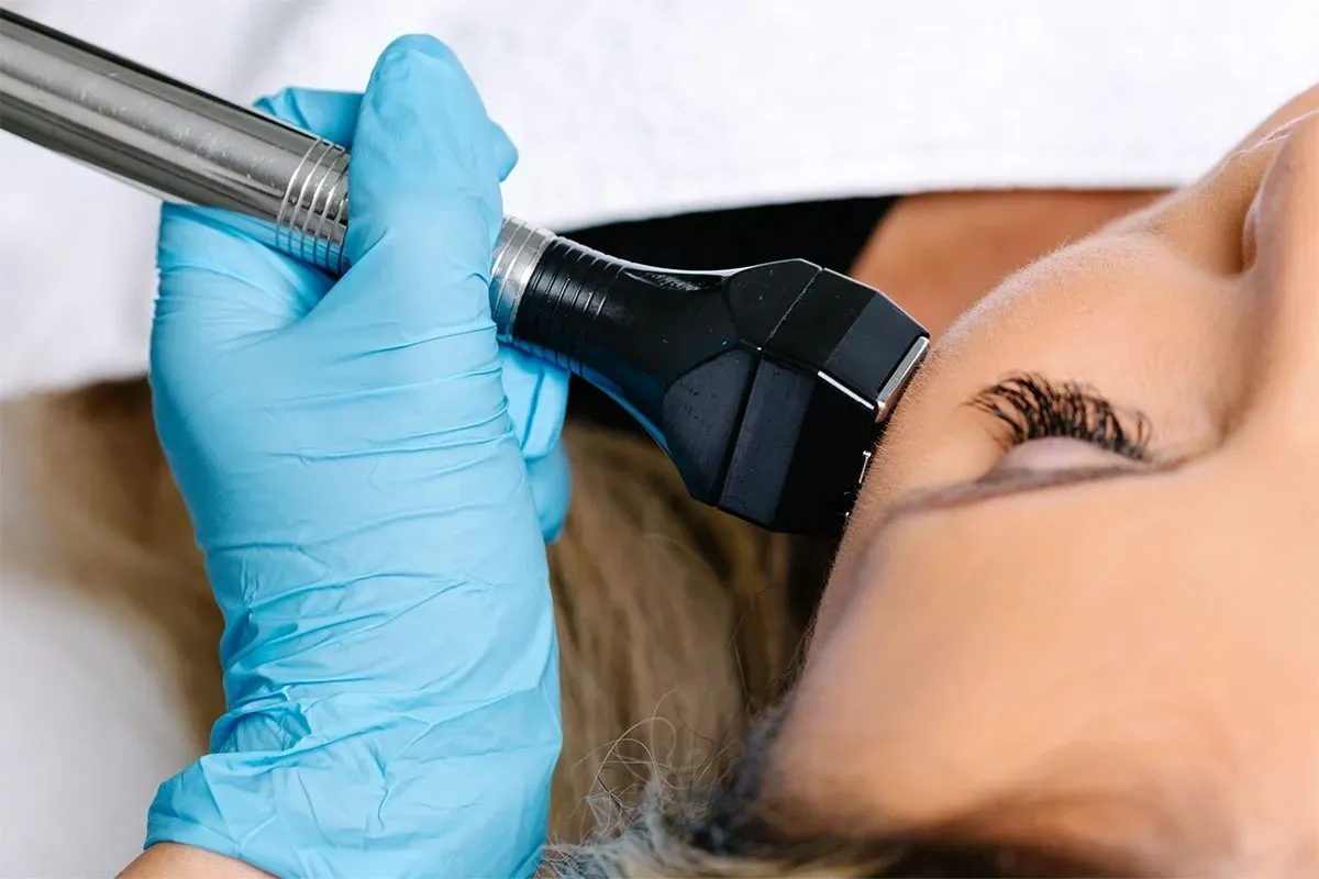 Practitioner in gloves using a radiofrequency handpiece around a patient's eye area